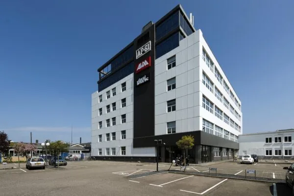 Modern kantoorgebouw aan de Anthony Fokkerweg met diverse bedrijfslogo’s en een parkeerterrein op de voorgrond.